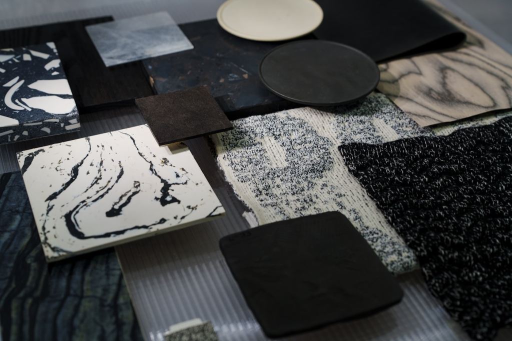 Neutral interior material samples arranged together, including wood, stone, and textiles.