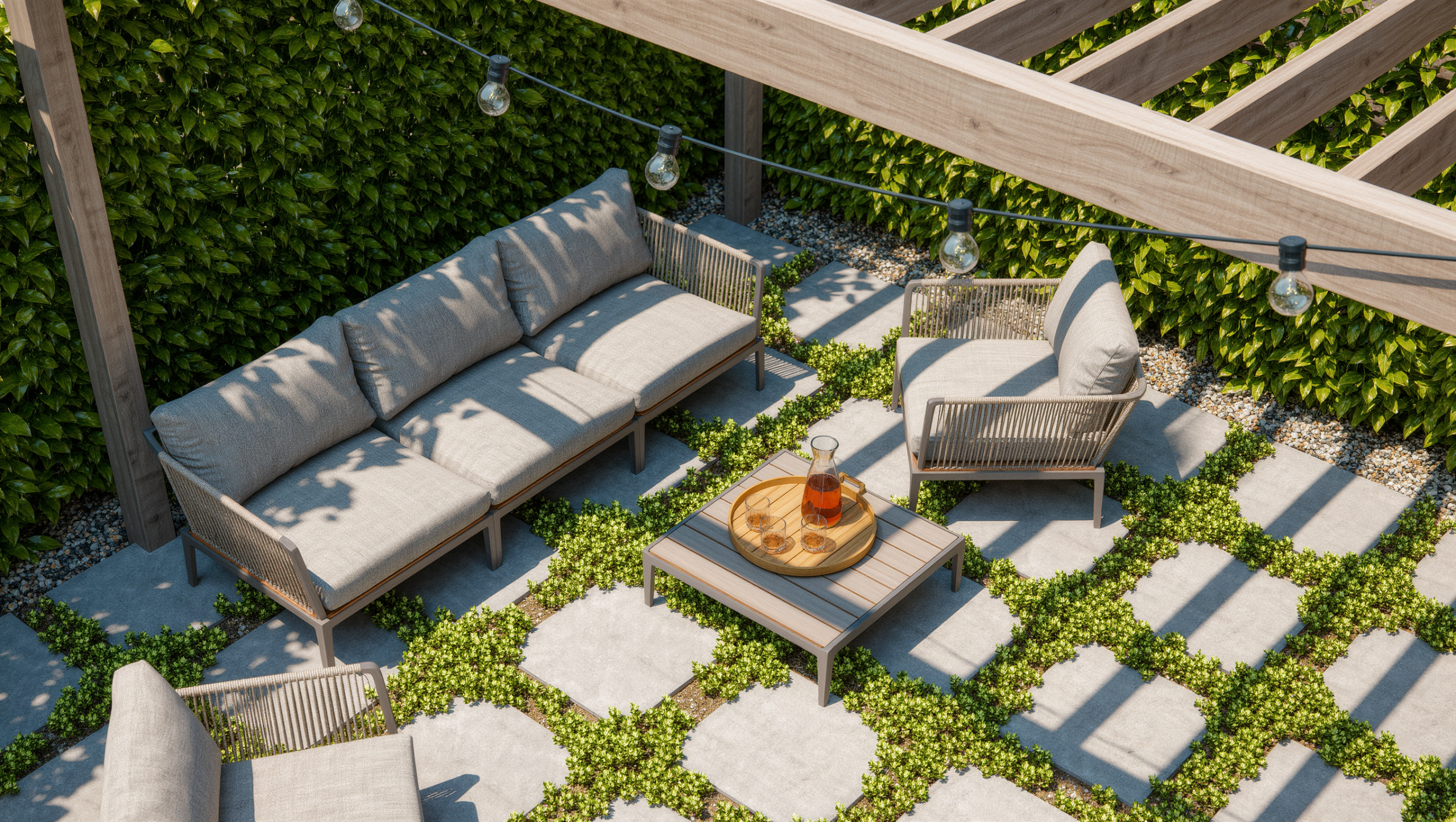 A level permeable-paver patio with thyme joints, a stable teak seating group, a low planted border, and bright midday sun under a pergola.
