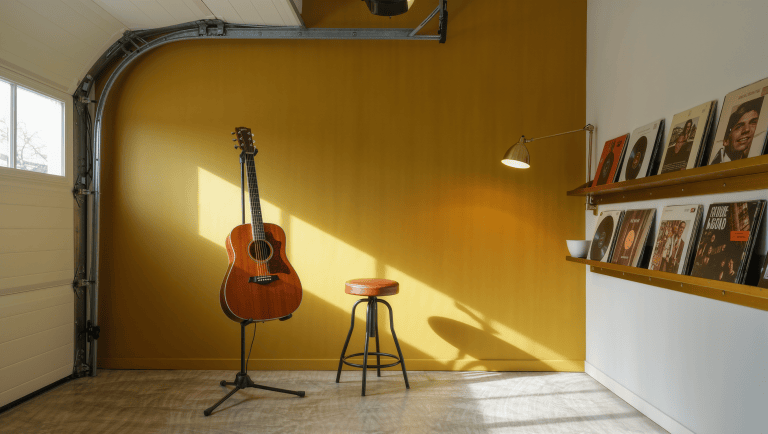 A mustard accent wall behind a guitar stand and leather stool in a converted garage music room.