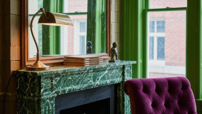 A leather wingback chair beside a rain-streaked window in a converted garden shed library.