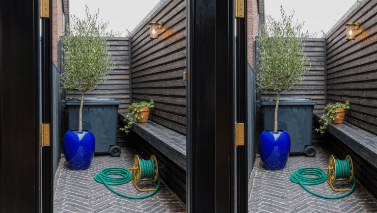 A narrow herringbone-brick side-yard passage with a wheeled bin discreetly tucked behind a brass-hinged timber screen, beside a glazed cobalt urn.