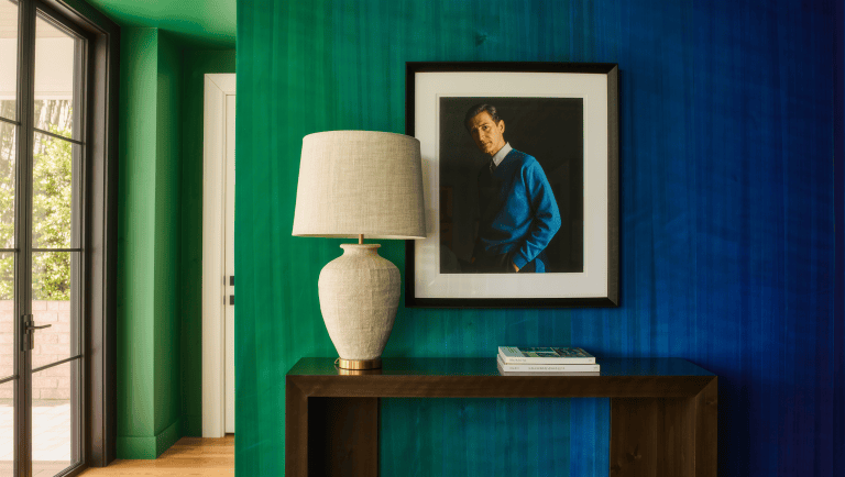 A console table is styled with one substantial ceramic lamp and one artwork rather than many small objects.