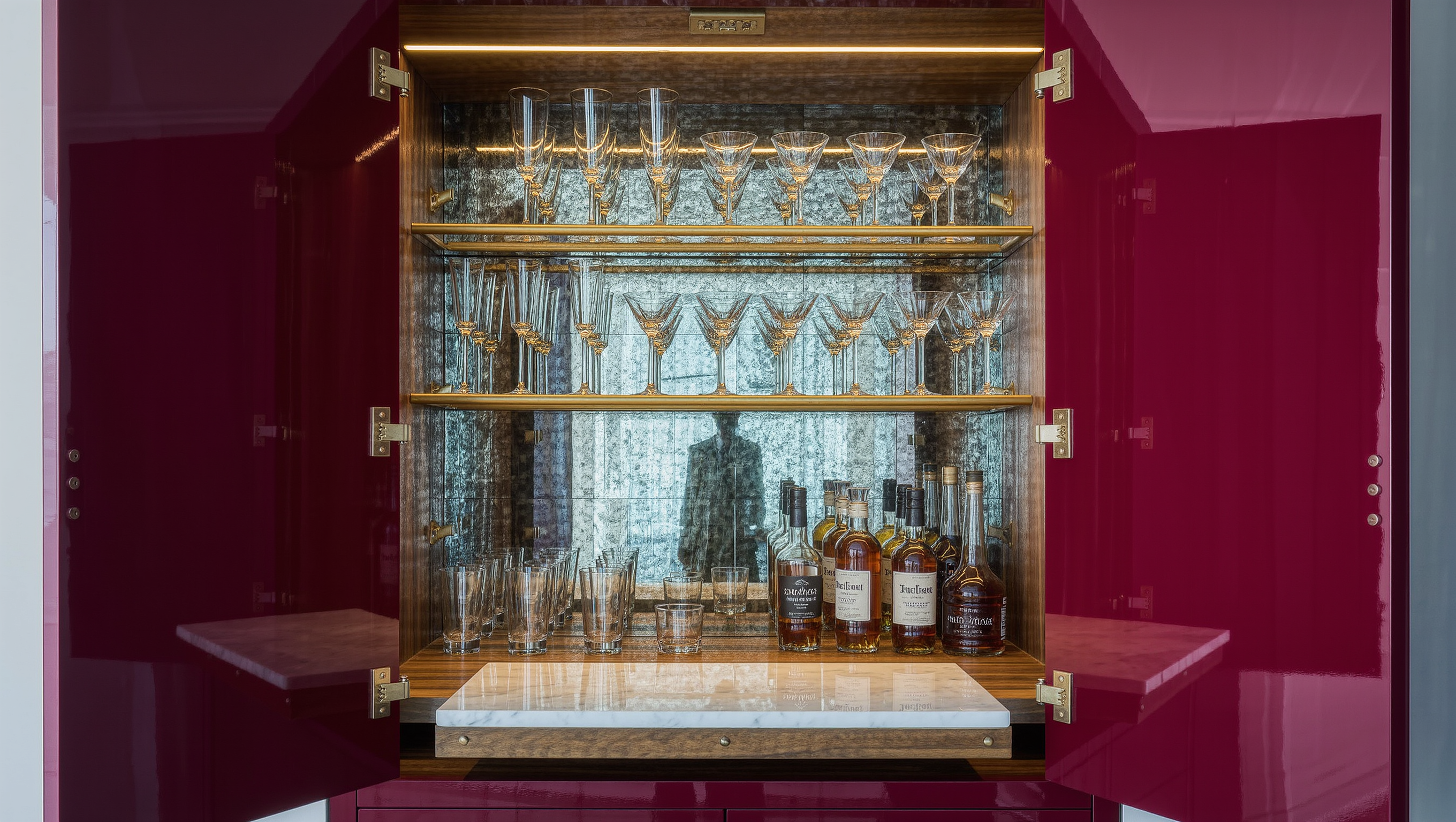 A lacquered burgundy closet bar opens to reveal mirrored shelves of glassware and bottles.