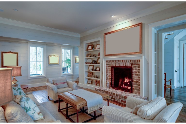 A brick fireplace with built-in shelving anchors a light-filled living room, with an open doorway beside it leading through to the next room.